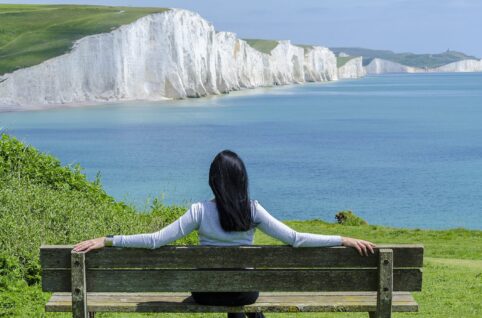 Woman Sitting on Deck Chair by Sea