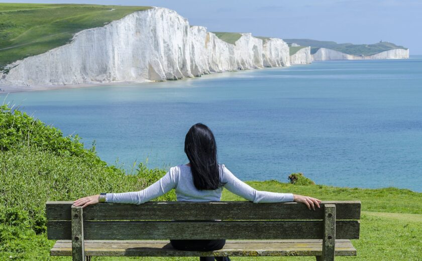 Woman Sitting on Deck Chair by Sea