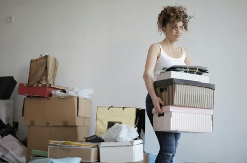 Concentrated woman carrying stack of cardboard boxes for relocation