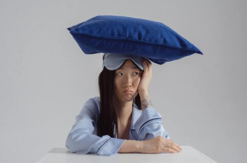 A Woman in Light Blue Long Sleeves with Pillow on Her Head